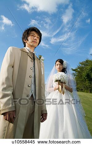 Stock Photography - Bride and bridegroom standing and looking away. Fotosearch