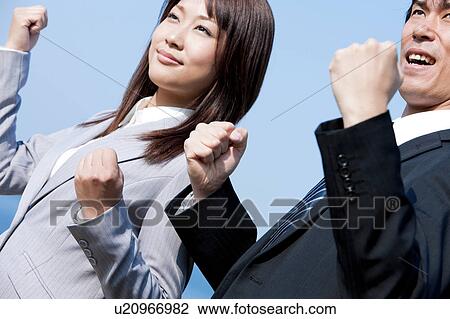 Stock Image - Business people making fists at beach . Fotosearch