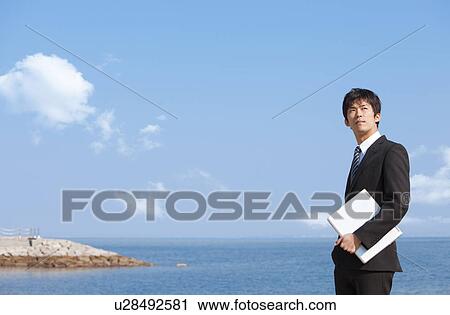 Stock Image - Businessman holding a laptop. Fotosearch