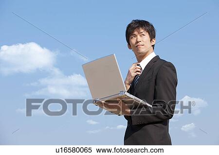 Stock Photography - Businessman holding a laptop. Fotosearch