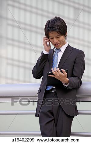 Businessman on mobile phone and using digital tablet outdoors View Large Photo Image Stock Photo - Businessman on mobile phone and using digital tablet outdoors. Fotosearch