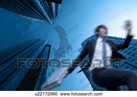 Stock Image - Businessman running between skyscraper with map in the background, digital composite. Fotosearch