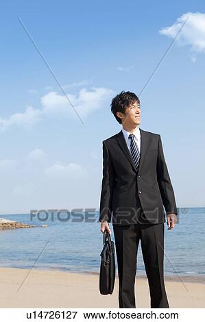 Businessman standing on the beach View Large Photo Image Stock Photo - Businessman standing on the beach. Fotosearch