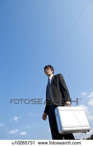 Businessman standing with briefcase View Large Photo Image Stock Image - Businessman standing with briefcase. Fotosearch