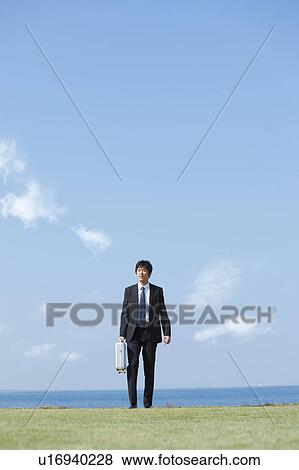 Businessman standing with briefcase View Large Photo Image Stock Photo - Businessman standing with briefcase. Fotosearch