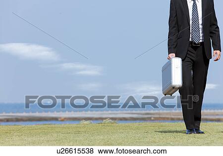 Businessman standing with briefcase View Large Photo Image Stock Photo - Businessman standing with briefcase. Fotosearch