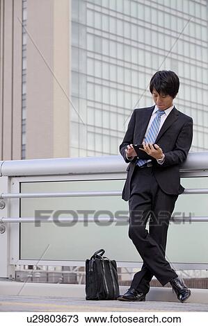 Stock Image - Businessman using digital tablet outdoors. Fotosearch
