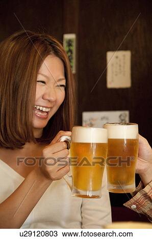 Stock Image - Couple toasting with beer. Fotosearch