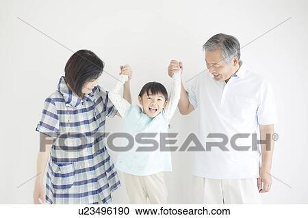 Stock Image - Grandparents Lifting Granddaughter From Hands. Fotosearch