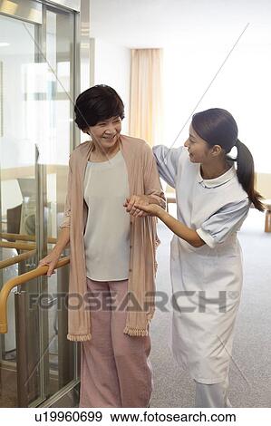 Stock Photo - Healthcare Worker Supporting Senior Woman To Walk. Fotosearch
