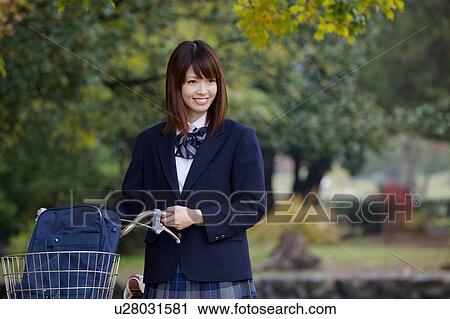 Stock Image - High school girl pushing bicycle. Fotosearch