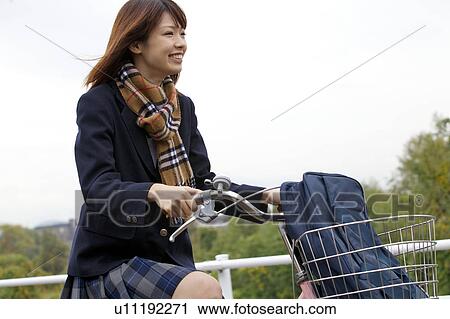 Stock Image - High school girl riding a bicycle. Fotosearch