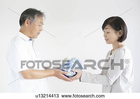 Stock Image - Mature Couple Holding Globe. Fotosearch