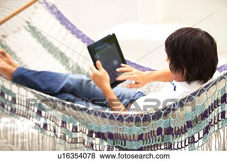 Mature man on a hammock using a digital tablet View Large Photo Image Stock Photo - Mature man on a hammock using a digital tablet. Fotosearch