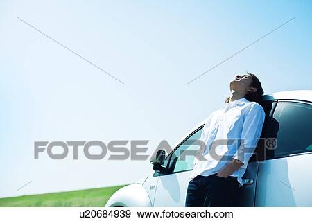 Stock Photo - Mid Adult Man Leaning Against Car. Fotosearch