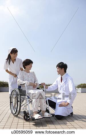Stock Photo - Nurse and Doctor with Female Patient in Wheelchair. Fotosearch