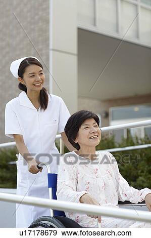 Stock Photo - Nurse Pushing Patient in Wheelchair. Fotosearch