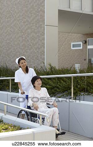 Stock Photography - Nurse Pushing Patient in Wheelchair. Fotosearch