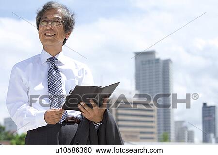 Stock Image - Senior businessman holding a diary. Fotosearch