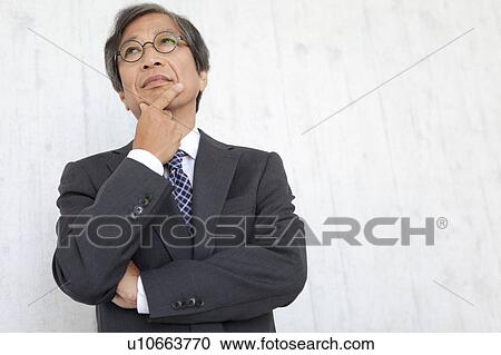 Stock Image - Senior businessman with hand on chin. Fotosearch