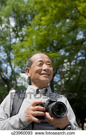 Stock Image - Senior man with camera. Fotosearch