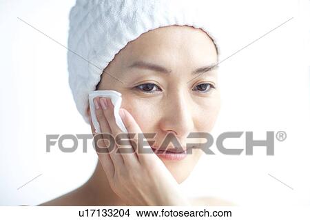 Picture - Woman cleaning her face with cotton ball. Fotosearch