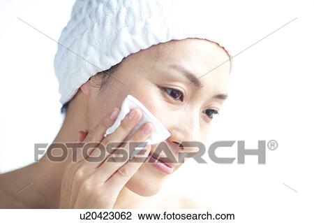 Stock Image - Woman cleaning her face with cotton ball. Fotosearch