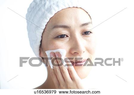 Stock Photo - Woman cleaning her face with cotton ball. Fotosearch