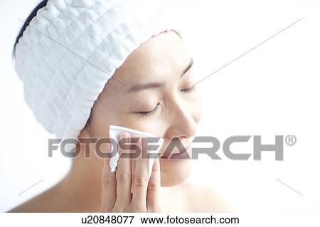 Woman cleaning her face with cotton ball View Large Photo Image Stock Photo - Woman cleaning her face with cotton ball. Fotosearch
