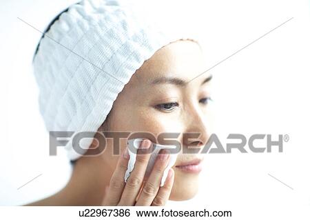 Stock Photograph - Woman cleaning her face with cotton ball. Fotosearch
