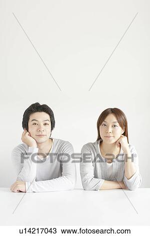 Stock Image - Young couple hand on chin looking at camera. Fotosearch