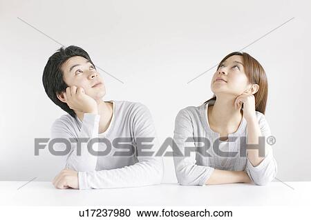 Stock Image - Young couple hand on chin looking up. Fotosearch