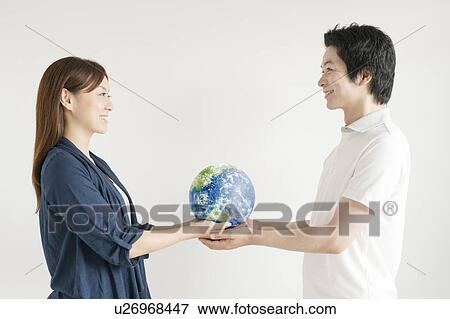 Stock Photo - Young couple holding globe. Fotosearch