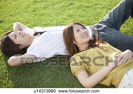 Stock Image - Young couple relaxing on grass. Fotosearch