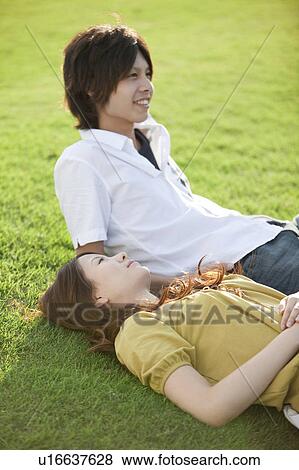 Young couple relaxing on grass View Large Photo Image Stock Photo - Young couple relaxing on grass. Fotosearch