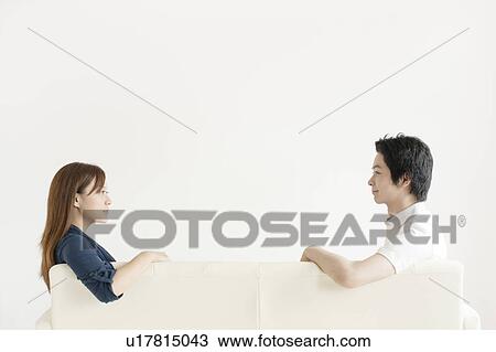 Young couple sitting on sofa View Large Photo Image Stock Image - Young couple sitting on sofa. Fotosearch