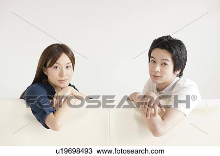 Stock Image - Young couple sitting on sofa. Fotosearch