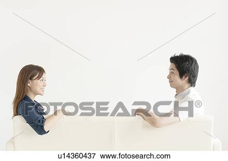 Stock Photo - Young couple sitting on sofa. Fotosearch