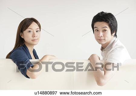 Stock Photo - Young couple sitting on sofa. Fotosearch