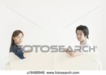 Young couple sitting on sofa View Large Photo Image Stock Photograph - Young couple sitting on sofa. Fotosearch