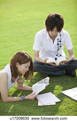 Young couple studying on grass View Large Photo Image Stock Image - Young couple studying on grass. Fotosearch
