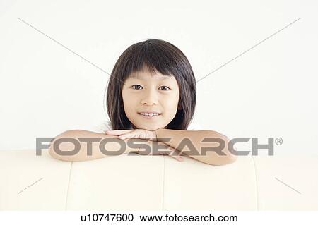 Stock Image - Young Girl Leaning Against Sofa. Fotosearch