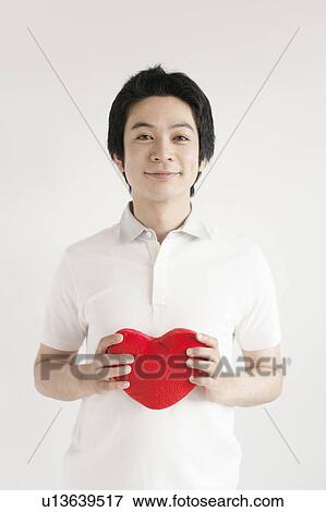 Stock Photo - Young man holding heart shape. Fotosearch