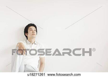 Young man sitting and looking away View Large Photo Image Stock Image - Young man sitting and looking away. Fotosearch