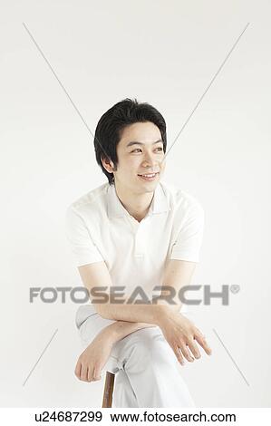 Young man sitting and looking away View Large Photo Image Stock Photo - Young man sitting and looking away. Fotosearch