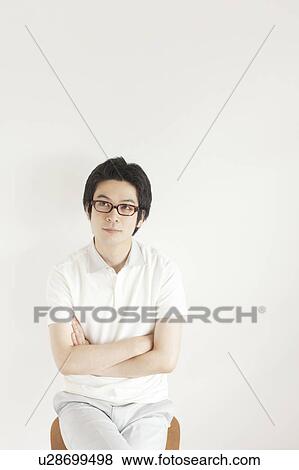 Stock Photo - Young man sitting and looking away. Fotosearch