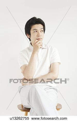 Stock Photography - Young man sitting and looking away. Fotosearch