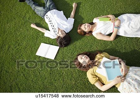 Young people lying down on grass View Large Photo Image Stock Photo - Young people lying down on grass. Fotosearch