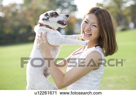 Young woman carrying a dog and looking at camera View Large Photo Image Stock Image - Young woman carrying a dog and looking at camera. Fotosearch