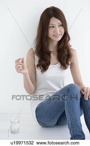 Stock Image - Young woman holding a Capsule. Fotosearch